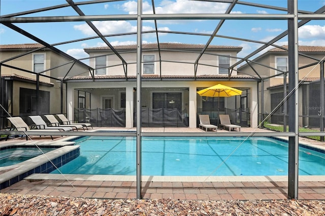 view of swimming pool with glass enclosure, a patio area, and an in ground hot tub