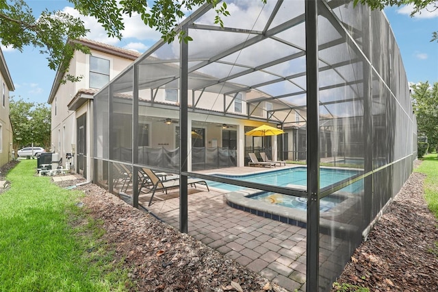 view of swimming pool with glass enclosure, a patio area, a yard, and ceiling fan