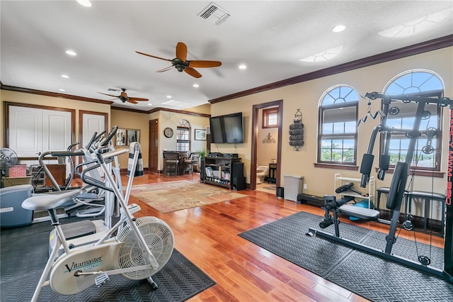 workout area with ceiling fan, light hardwood / wood-style floors, ornamental molding, and a textured ceiling