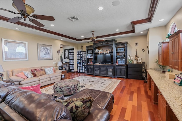 living room featuring a textured ceiling, dark hardwood / wood-style flooring, a tray ceiling, and crown molding