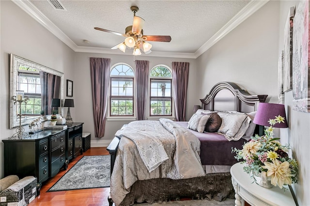 bedroom featuring multiple windows, ceiling fan, a textured ceiling, and hardwood / wood-style flooring