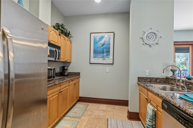 kitchen with dark stone counters, sink, and stainless steel appliances