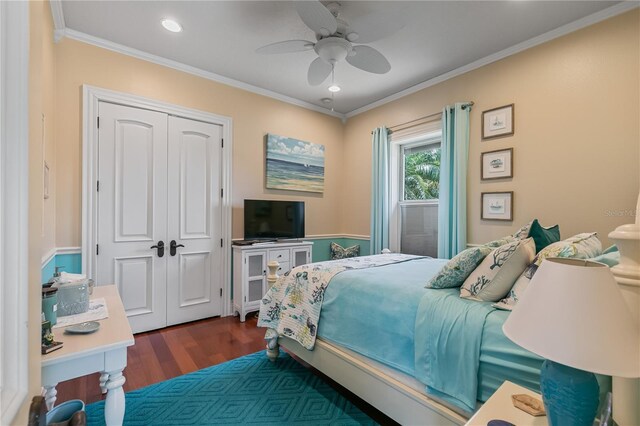 bedroom with crown molding, ceiling fan, a closet, and dark wood-type flooring