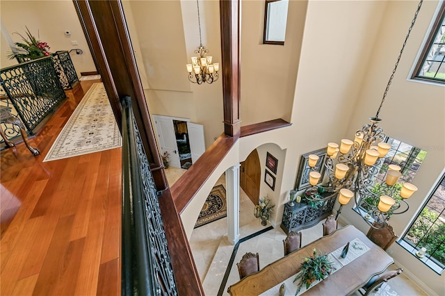 interior space featuring a towering ceiling, wood-type flooring, and a notable chandelier