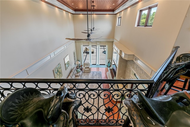 stairs featuring a towering ceiling, crown molding, ceiling fan, and wooden ceiling