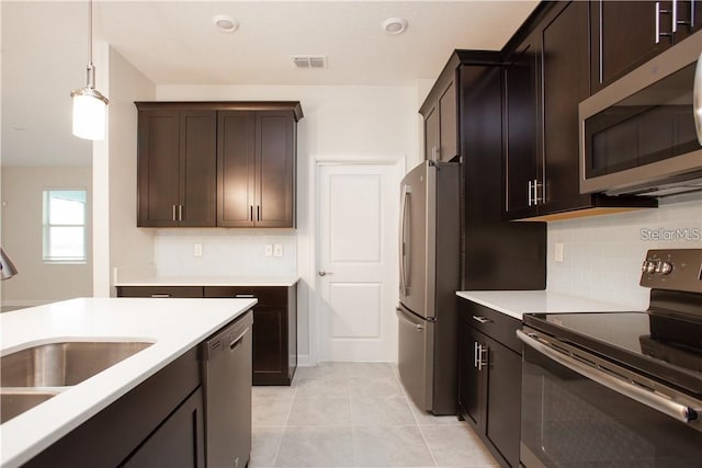 kitchen featuring dark brown cabinetry, sink, hanging light fixtures, stainless steel appliances, and light tile patterned floors