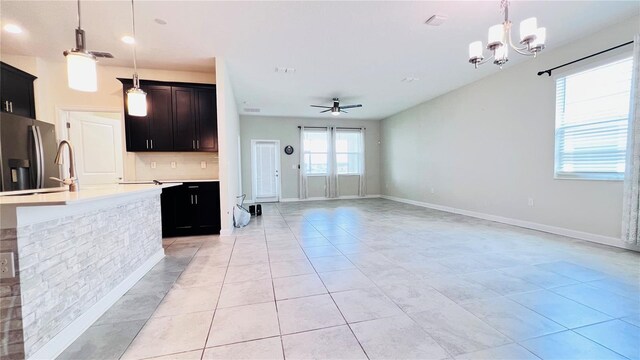 kitchen featuring backsplash, ceiling fan with notable chandelier, light tile patterned floors, decorative light fixtures, and stainless steel fridge with ice dispenser