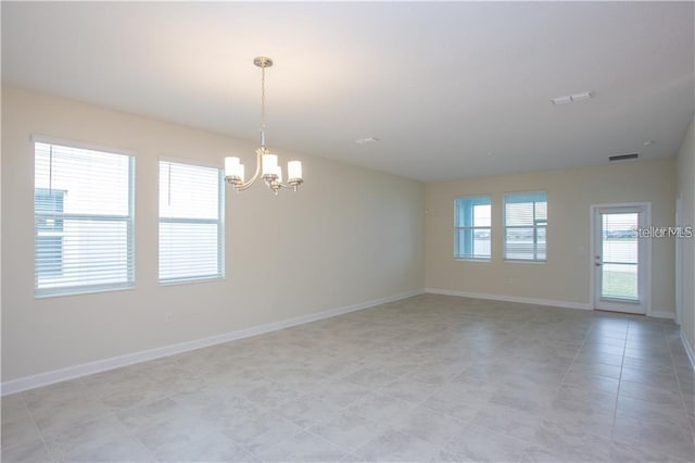 tiled spare room with a chandelier