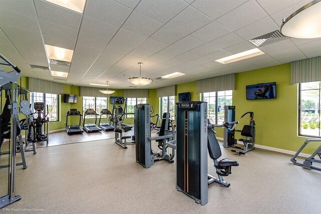 exercise room featuring a paneled ceiling and plenty of natural light