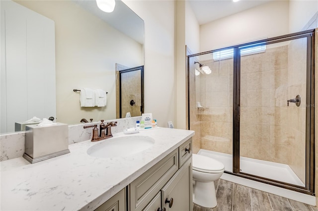 bathroom with hardwood / wood-style floors, vanity, toilet, and a shower with door