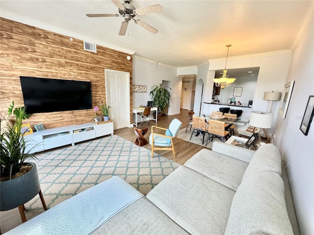 living room with crown molding, ceiling fan with notable chandelier, and hardwood / wood-style floors