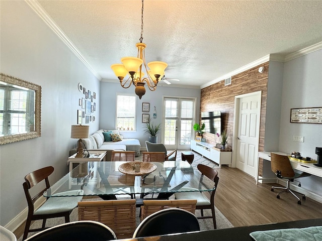 dining room with an inviting chandelier, wooden walls, crown molding, and a textured ceiling