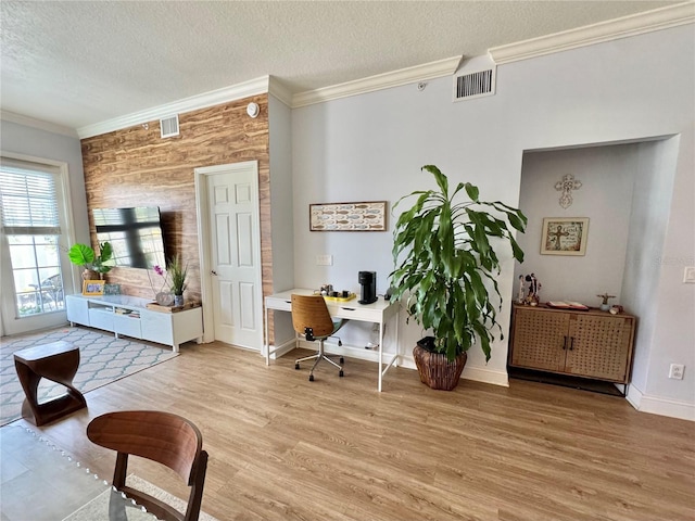 office area featuring wooden walls, crown molding, a textured ceiling, and light hardwood / wood-style floors