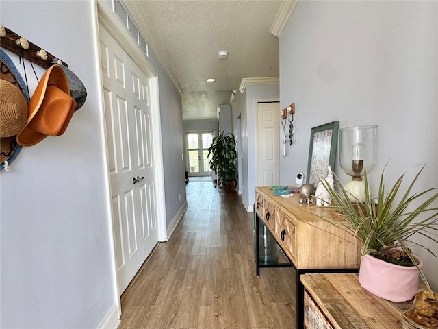 corridor featuring a textured ceiling, ornamental molding, and hardwood / wood-style floors