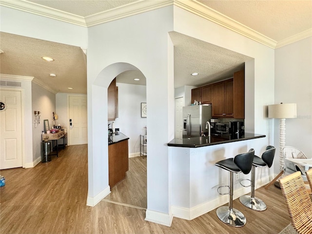 kitchen featuring stainless steel fridge with ice dispenser, kitchen peninsula, a textured ceiling, and light hardwood / wood-style flooring