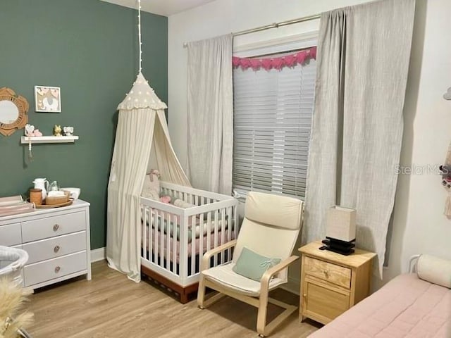 bedroom featuring light wood-type flooring and a crib