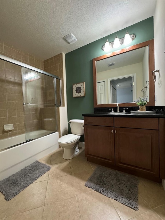 full bathroom with a textured ceiling, tile patterned floors, vanity, toilet, and combined bath / shower with glass door