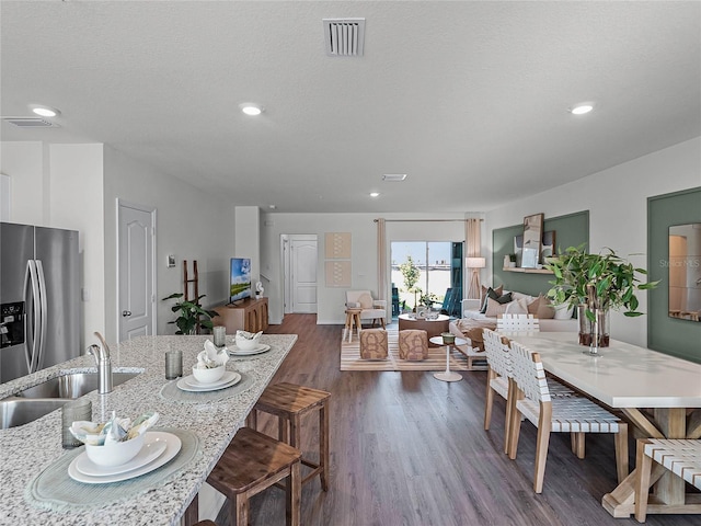 dining room with sink, dark wood-type flooring, and a textured ceiling