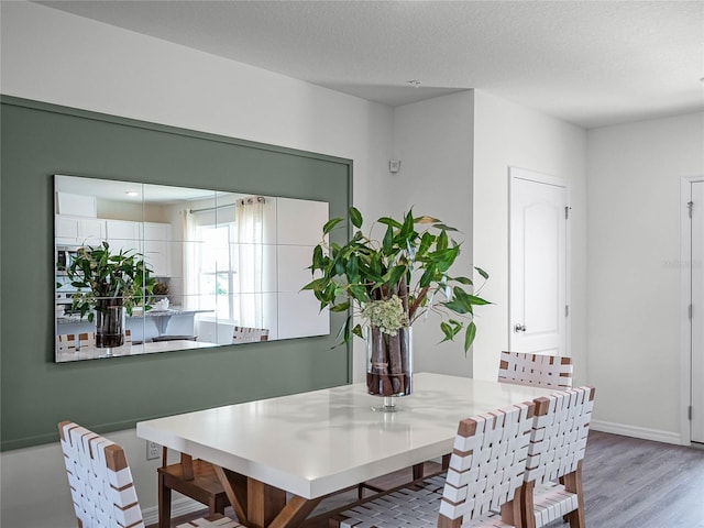 dining space with light wood-type flooring and a textured ceiling