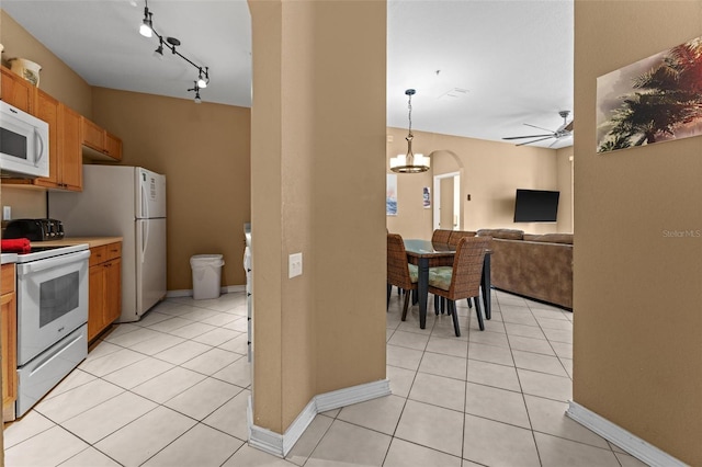 kitchen with light tile patterned flooring, ceiling fan with notable chandelier, hanging light fixtures, track lighting, and white appliances