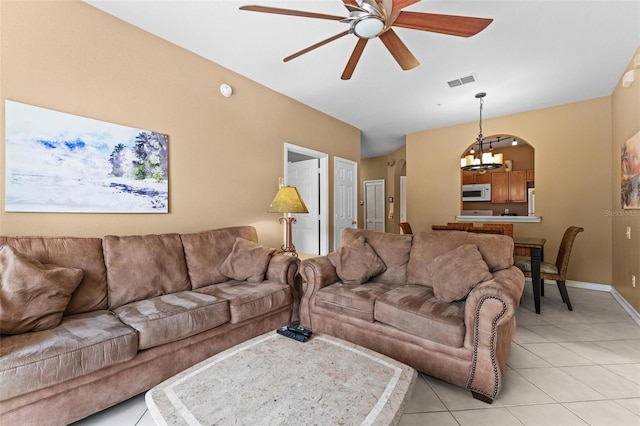 tiled living room featuring ceiling fan with notable chandelier