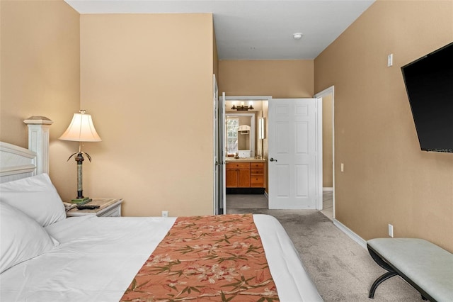 bedroom with ensuite bathroom and carpet flooring