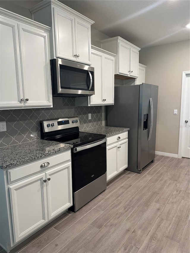 kitchen featuring white cabinets, backsplash, stainless steel appliances, and light hardwood / wood-style flooring