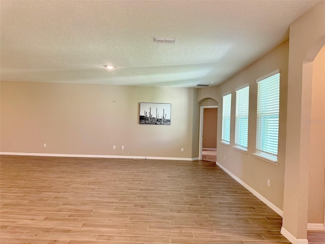 spare room with a textured ceiling and light wood-type flooring