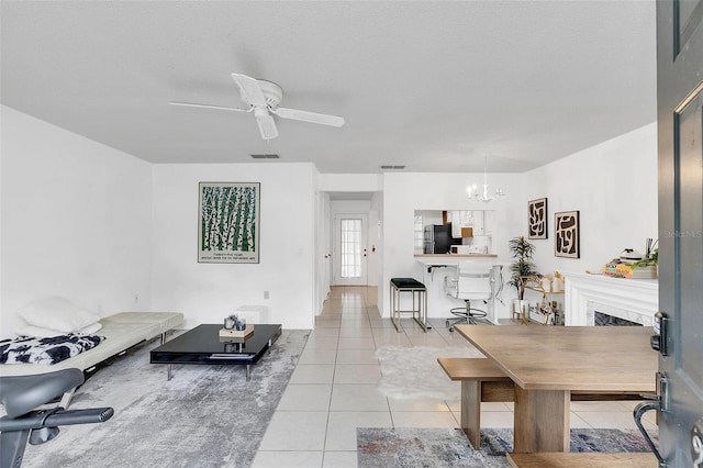 tiled living room featuring ceiling fan with notable chandelier