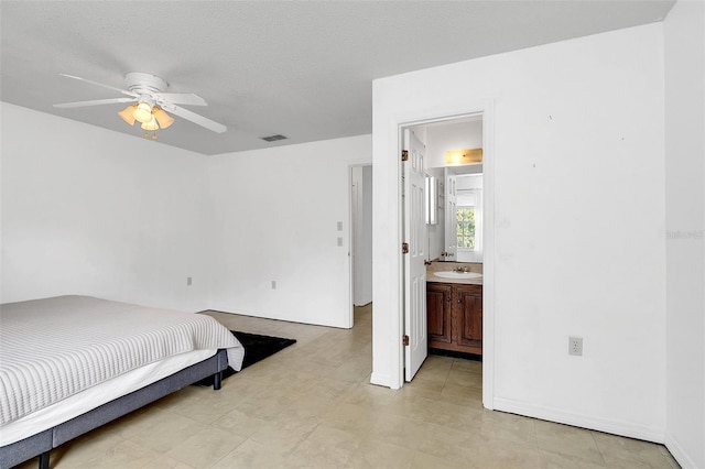 bedroom featuring ensuite bathroom, sink, ceiling fan, and a textured ceiling