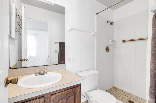 bathroom featuring a tile shower, vanity, and toilet