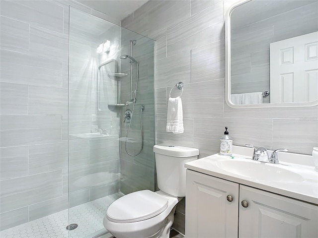 bathroom featuring vanity, toilet, tiled shower, and tile walls