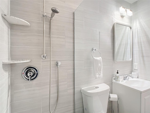 bathroom with vanity, toilet, tiled shower, and tile walls