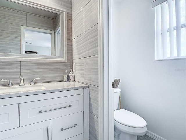 bathroom with vanity, tile walls, and toilet