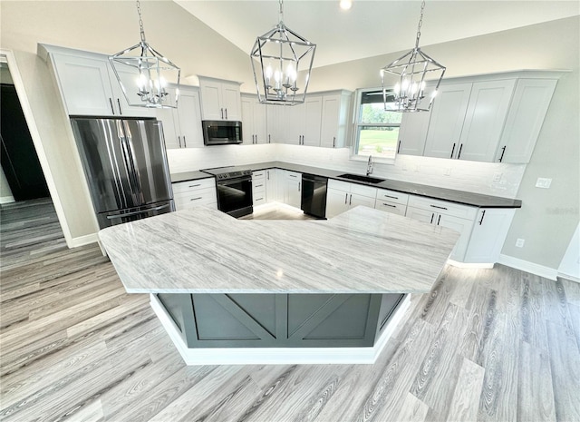 kitchen with light hardwood / wood-style flooring, stainless steel appliances, pendant lighting, backsplash, and sink