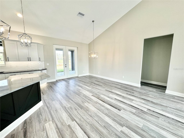 interior space featuring high vaulted ceiling, a chandelier, light hardwood / wood-style floors, and french doors