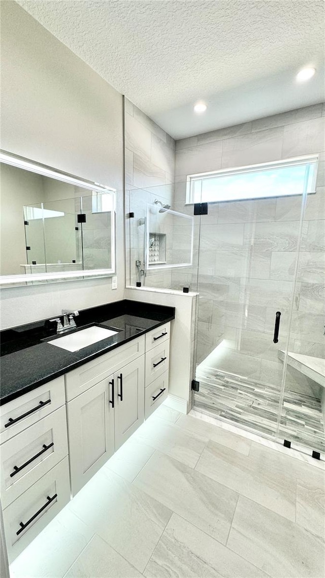 bathroom with tile floors, a textured ceiling, an enclosed shower, and vanity