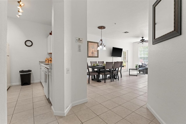 hallway with track lighting, light tile floors, and an inviting chandelier