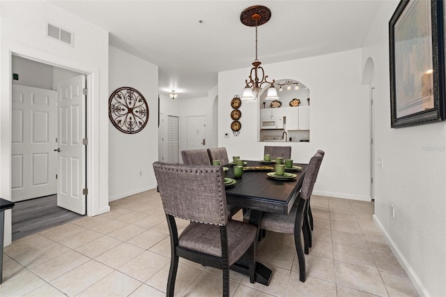 tiled dining room with a notable chandelier