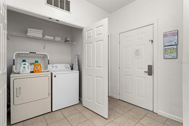 laundry area featuring washer and clothes dryer and light tile floors