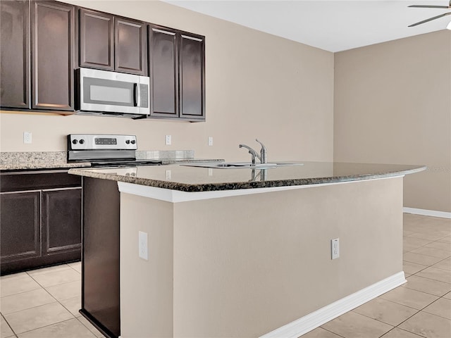 kitchen with a kitchen island with sink, sink, light tile patterned floors, dark brown cabinets, and range