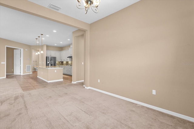 unfurnished living room with an inviting chandelier and light colored carpet