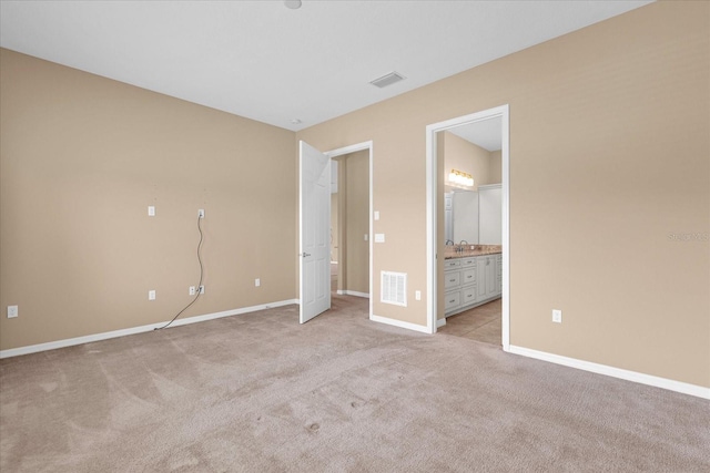 unfurnished bedroom with sink, light carpet, and ensuite bath