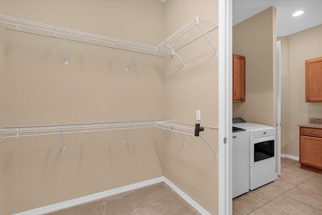 washroom with cabinets, washing machine and dryer, and light tile patterned floors