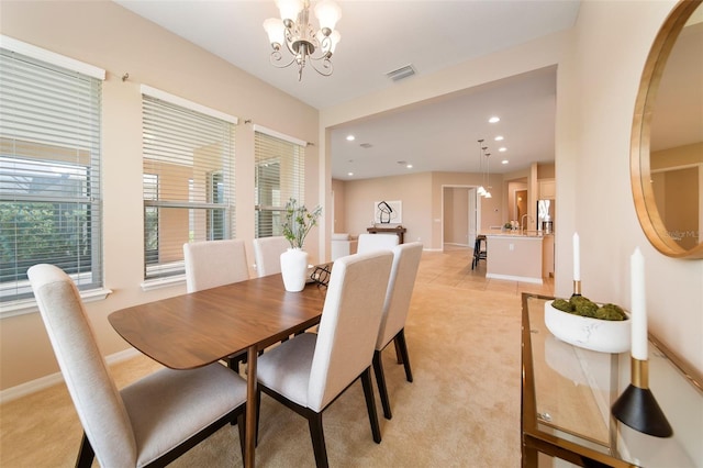 carpeted dining space with an inviting chandelier