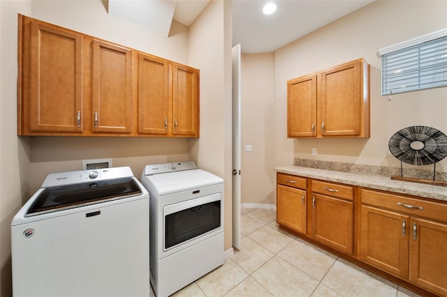 laundry area with washing machine and dryer, cabinets, and light tile patterned flooring