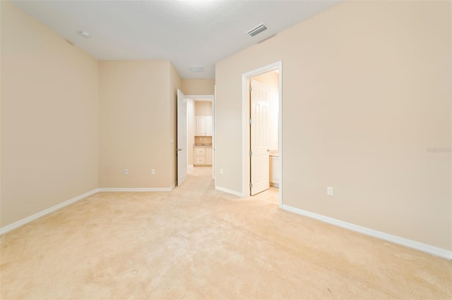 interior space featuring light carpet and ensuite bath