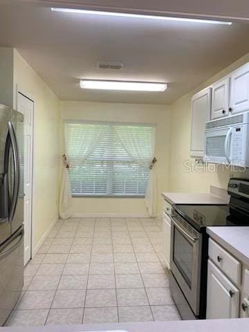 kitchen with white cabinets, light tile patterned floors, and stainless steel appliances