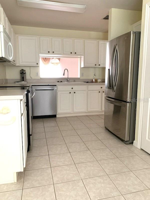 kitchen with sink, white cabinets, light tile patterned floors, and appliances with stainless steel finishes