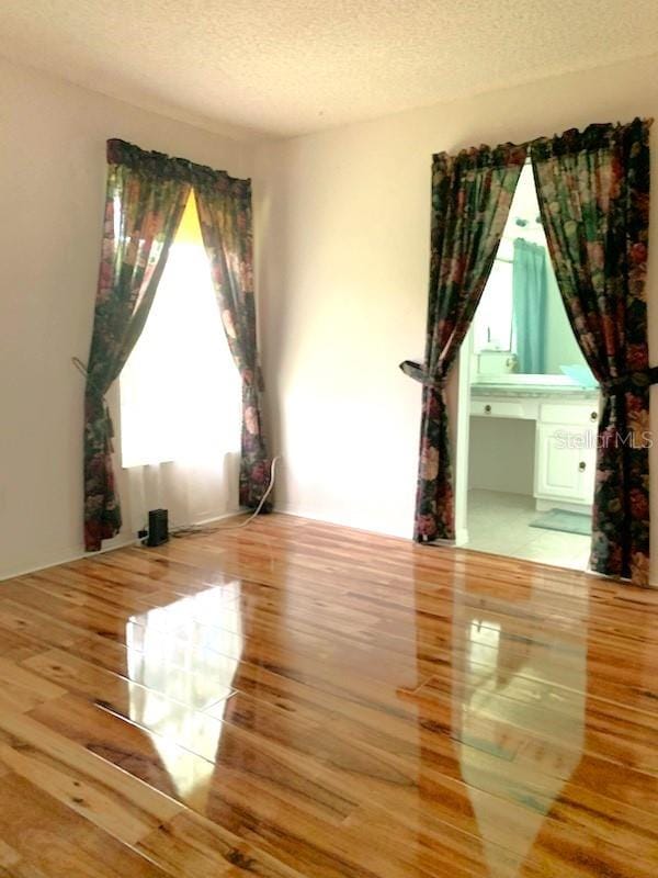 unfurnished room with wood-type flooring and a textured ceiling